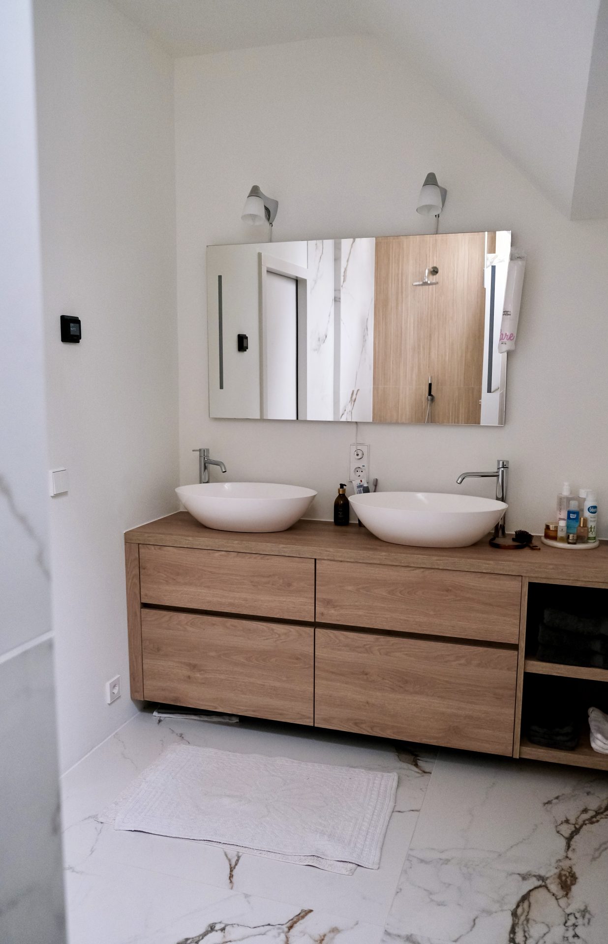 Moderne badkamer met twee opzetwastafels op een houten onderkast en spiegels, verlicht door natuurlijk daglicht