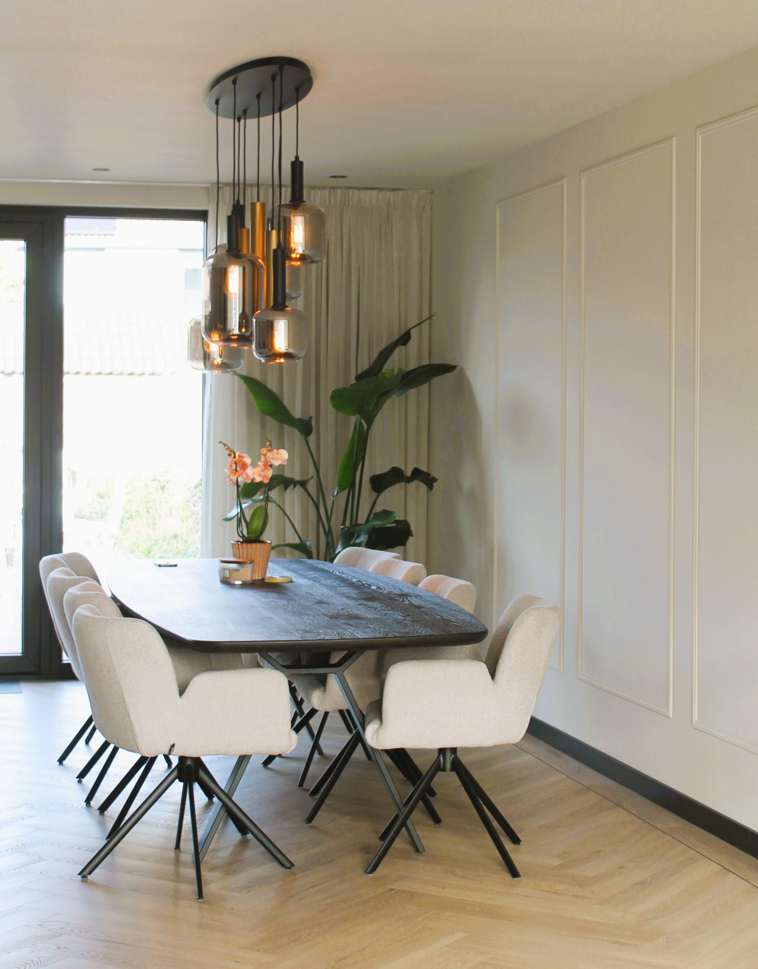 Moderne eetkamer na renovatie in Spakenburg met houten eettafel, design stoelen, hanglampen en groene planten