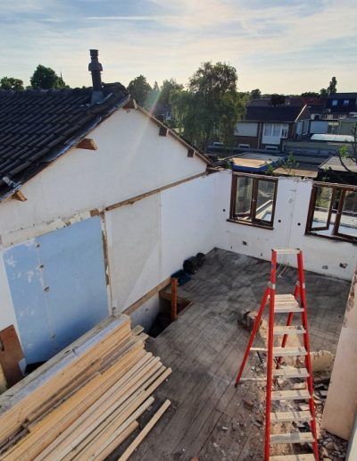 Overzichtsfoto van de achterzijde van de woning in Hilversum tijdens de sloopfase, met zichtbare kale muren en een rode ladder op de bouwvloer, uitgevoerd door Bouwbedrijf Hop.