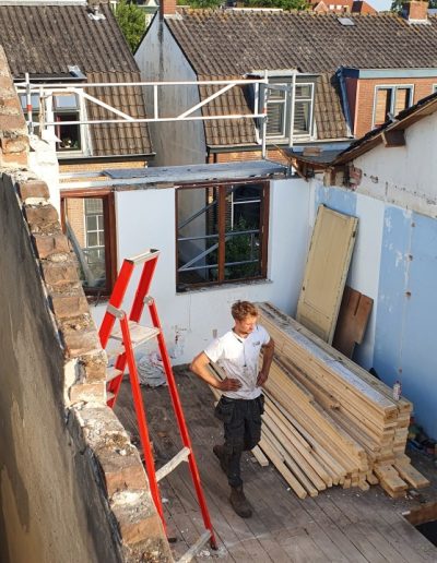 Bovenaanzicht van de achterzijde van de woning in Hilversum tijdens de sloopfase, met een medewerker van Bouwbedrijf Hop die bouwmaterialen verplaatst.