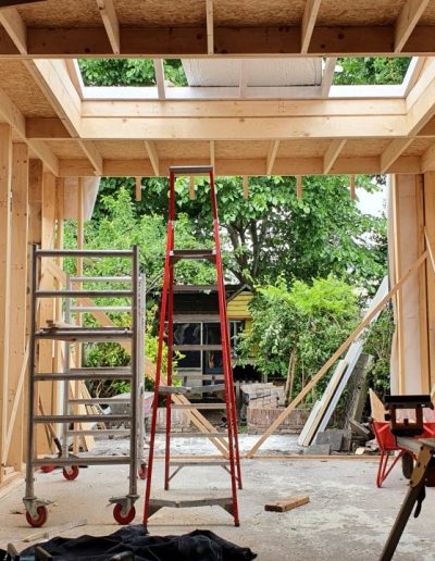 Interieur van de nieuwe uitbouw in Hilversum tijdens de bouwfase, met zichtbare houtskeletconstructie en een geplaatste lichtkoepel in het plafond, uitgevoerd door Bouwbedrijf Hop.