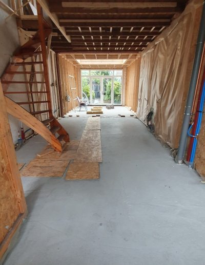 Interieur van de woning in Hilversum tijdens de renovatie, met zichtbare houtskeletbouw, nieuwe leidingen en een betonnen vloer, uitgevoerd door Bouwbedrijf Hop.