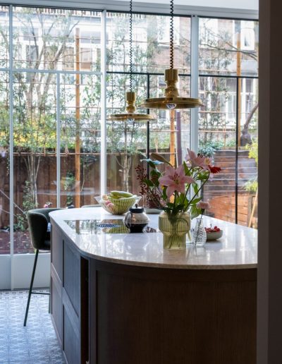 Moderne eetkamer na renovatie in Spakenburg met eettafel, bloemen en grote raampartijen met uitzicht op tuin