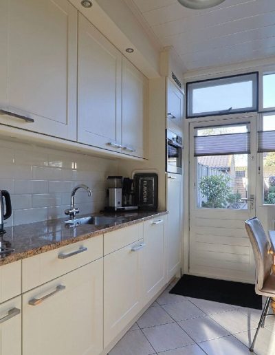 Oude keuken vóór renovatie in Spakenburg met verouderde kasten, donker werkblad en eenvoudige afwerking