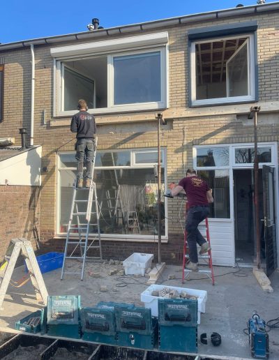 Gevelrenovatie van woning in Spakenburg met vakmensen op ladder en steiger tijdens bouwwerkzaamheden