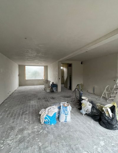 Woonkamer tijdens renovatie in Spakenburg met lege ruimte, bouwmaterialen en onafgewerkte wanden